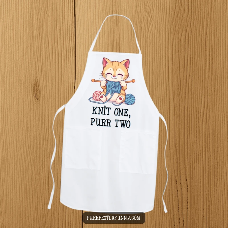 Funny cat attempting to knit with comically large yarn and needles on a functional and humorous funny apron.